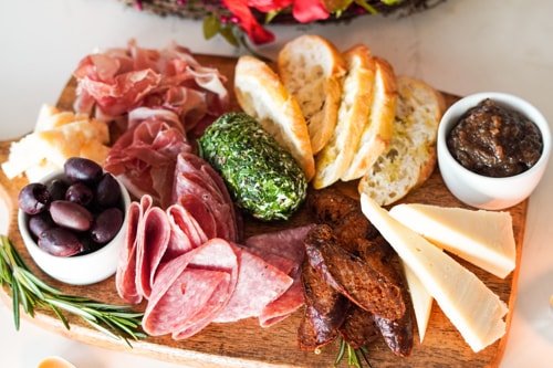 Charcuterie board with olives, bread, meats and cheeses.